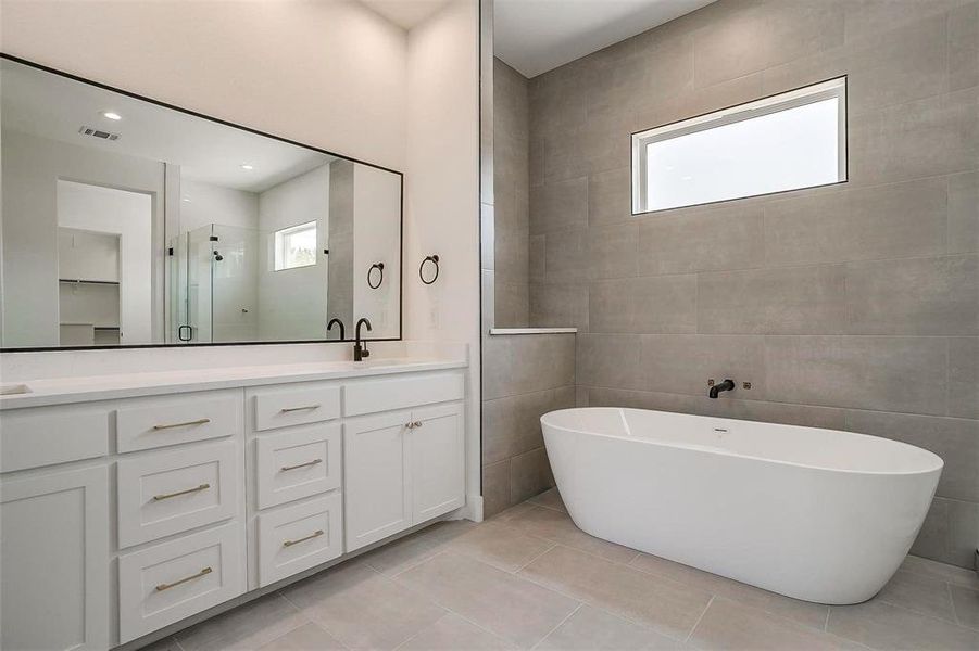 Full bath with plenty of natural light, a shower stall, double vanity, a freestanding bath, and tile walls Full bath with plenty of natural light, a shower stall, double vanity, a freestanding bath, and tile walls