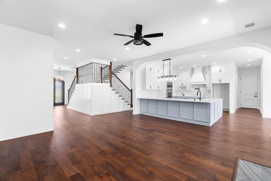 Unfurnished living room featuring arched walkways, dark wood-type flooring, stairway, a ceiling fan, and recessed lighting Unfurnished living room featuring arched walkways, dark wood-type flooring, stairway, a ceiling fan, and recessed lighting