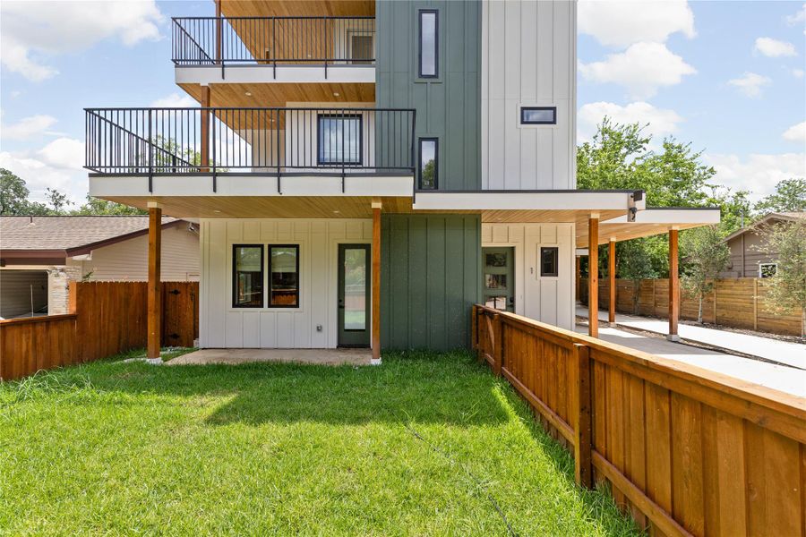 Rear view of property featuring board and batten siding, a patio, a balcony, and a fenced backyard