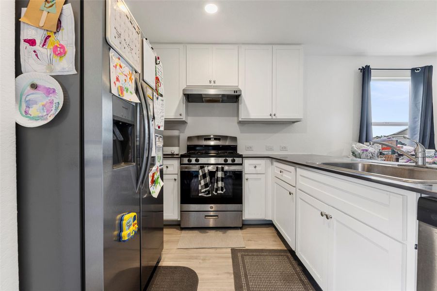 A well-appointed kitchen features sleek white cabinetry and durable flooring, perfect for daily living.