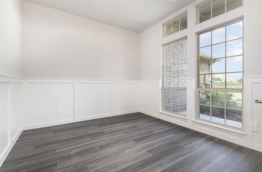 Empty room with a decorative wall, a wainscoted wall, and dark wood-type flooring Empty room with a decorative wall, a wainscoted wall, and dark wood-type flooring