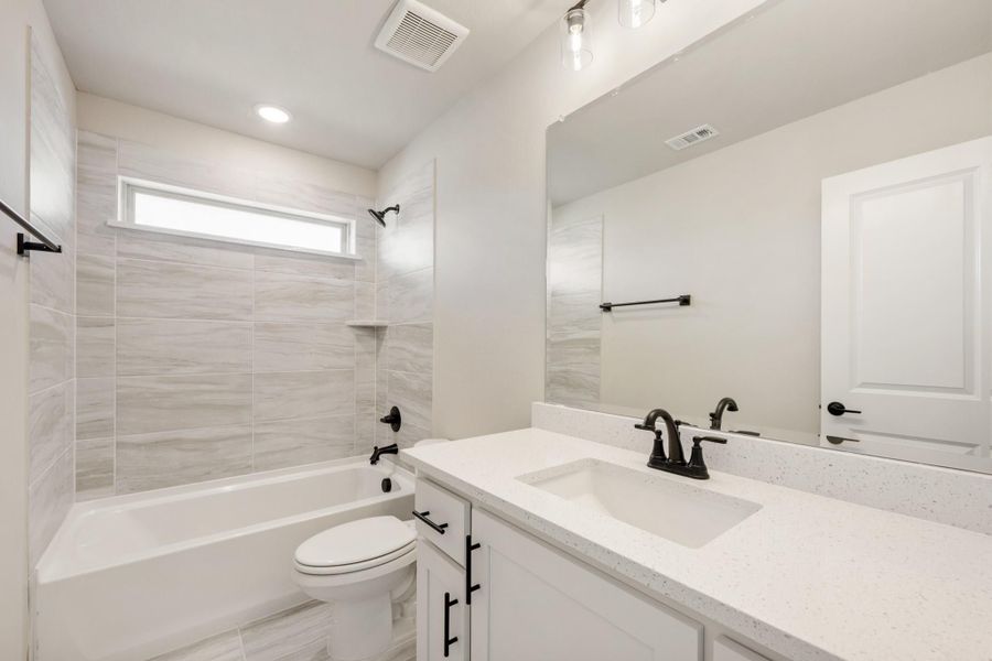 Bathroom with white quartz vanity, tiled shower-tub combo, and black hardware fixtures Bathroom with white quartz vanity, tiled shower-tub combo, and black hardware fixtures