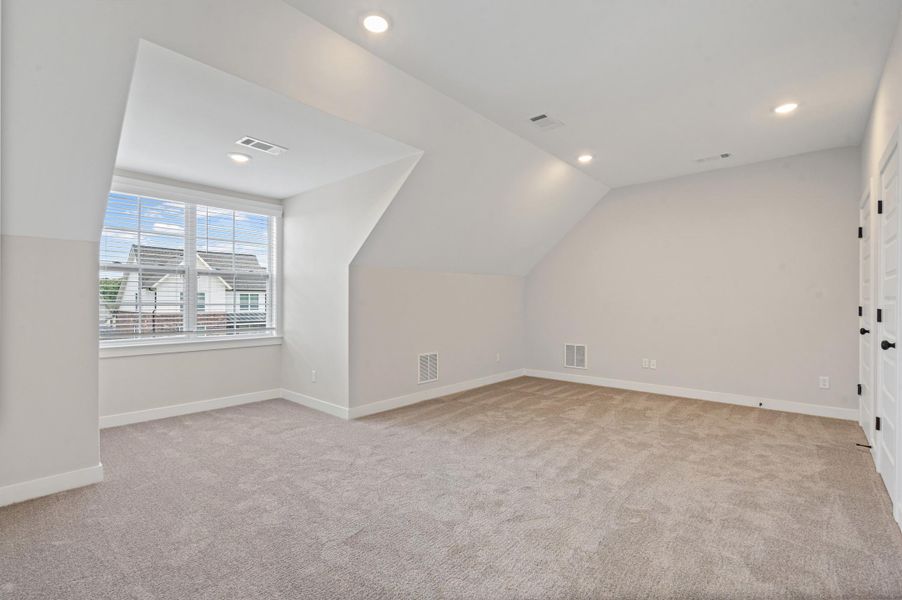Carpeted room featuring a double window with blinds, recessed lighting, white trim, and two white paneled doors with black hardware Carpeted room featuring a double window with blinds, recessed lighting, white trim, and two white paneled doors with black hardware