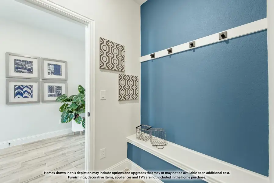 Mudroom entryway with blue accent wall, coat hooks, built-in bench, and view into adjacent room with framed wall art Mudroom entryway with blue accent wall, coat hooks, built-in bench, and view into adjacent room with framed wall art
