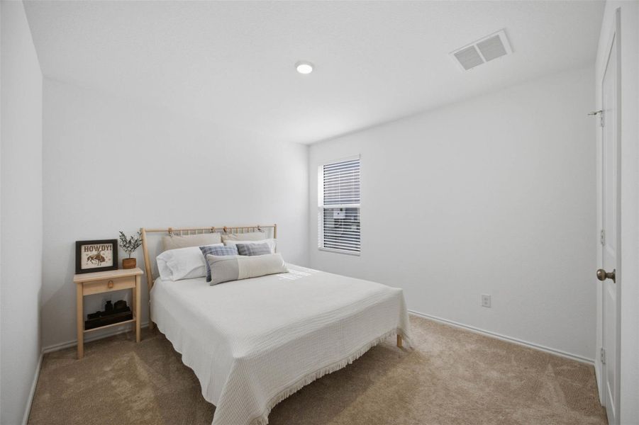 A window brings natural light into this serene bedroom featuring wall-to-wall carpeting.