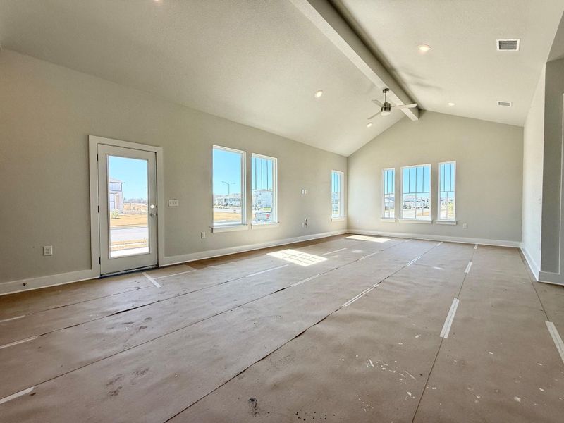 Unfurnished living room featuring baseboards, plenty of natural light, high vaulted ceiling, and beamed ceiling