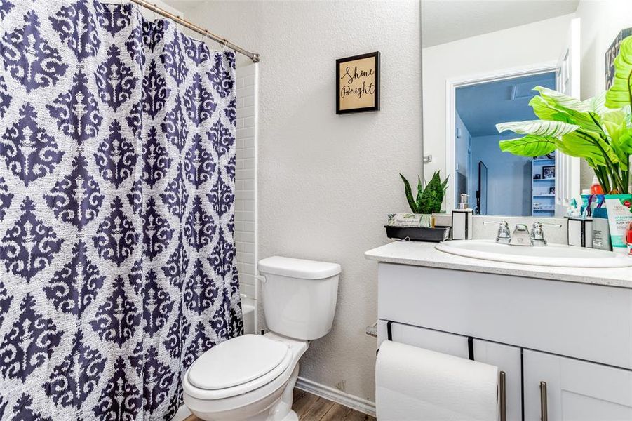 Full bathroom with toilet, shower / bath combination with curtain, hardwood / wood-style floors, and vanity