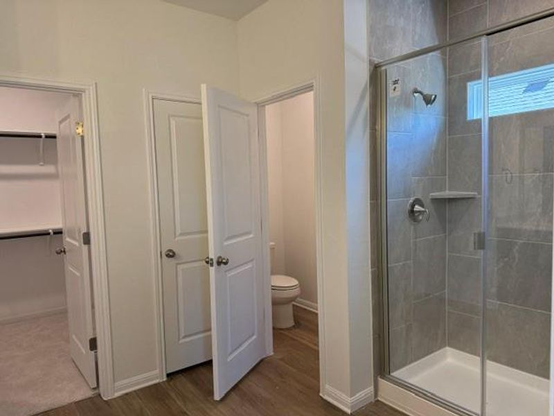 Walk-in shower with full-height gray tile surround, integrated shelf, and clear glass enclosure Walk-in shower with full-height gray tile surround, integrated shelf, and clear glass enclosure