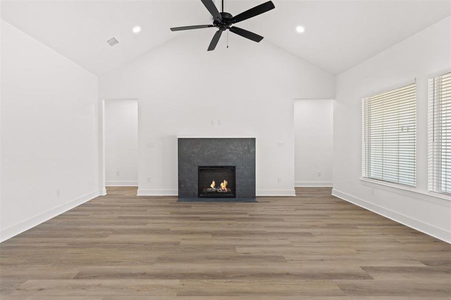 Unfurnished living room with dark wood finished floors, a fireplace, ceiling fan, lofted ceiling, and recessed lighting