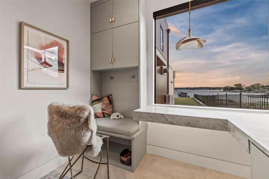 Built-in desk area featuring a stone countertop, integrated bench seating, and custom cabinetry with brass hardware
