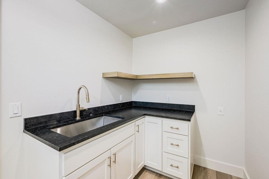 Compact prep and utility space with quartz-style counters, deep stainless sink, and open shelving—ideal for convenience and functionality. Compact prep and utility space with quartz-style counters, deep stainless sink, and open shelving—ideal for convenience and functionality.