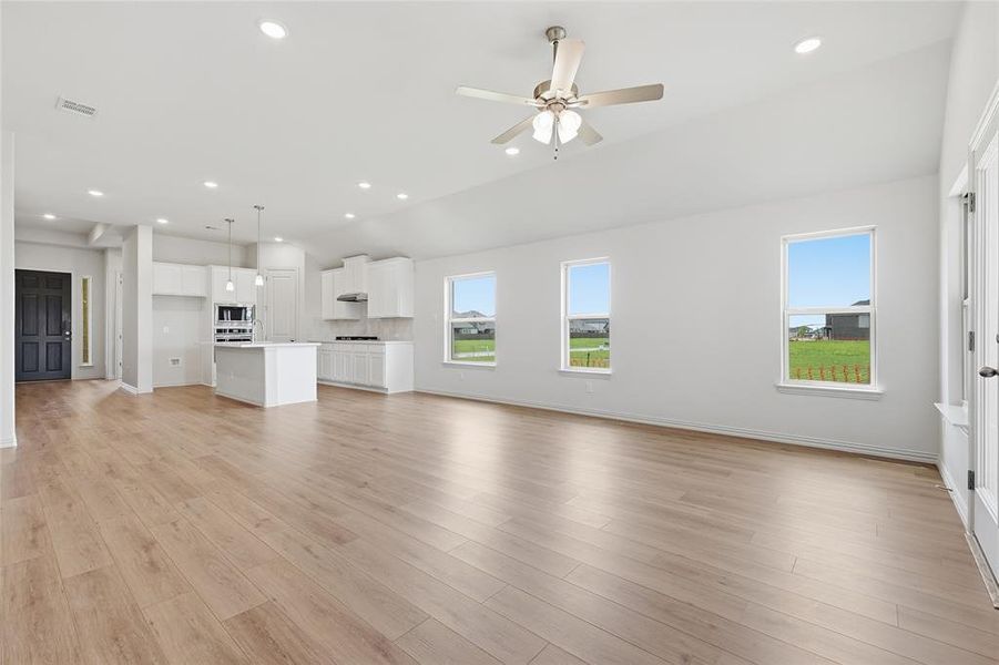 Unfurnished living room featuring ceiling fan, light wood-style flooring, recessed lighting, and lofted ceiling