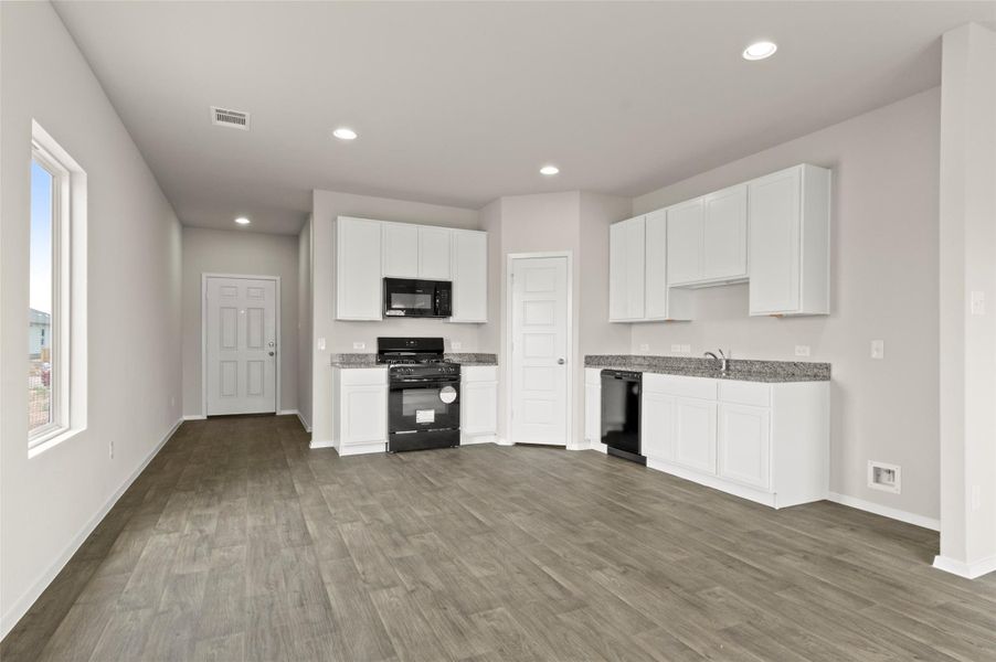 Kitchen with black appliances, white cabinets, recessed lighting, dark wood-style floors, and light stone countertops