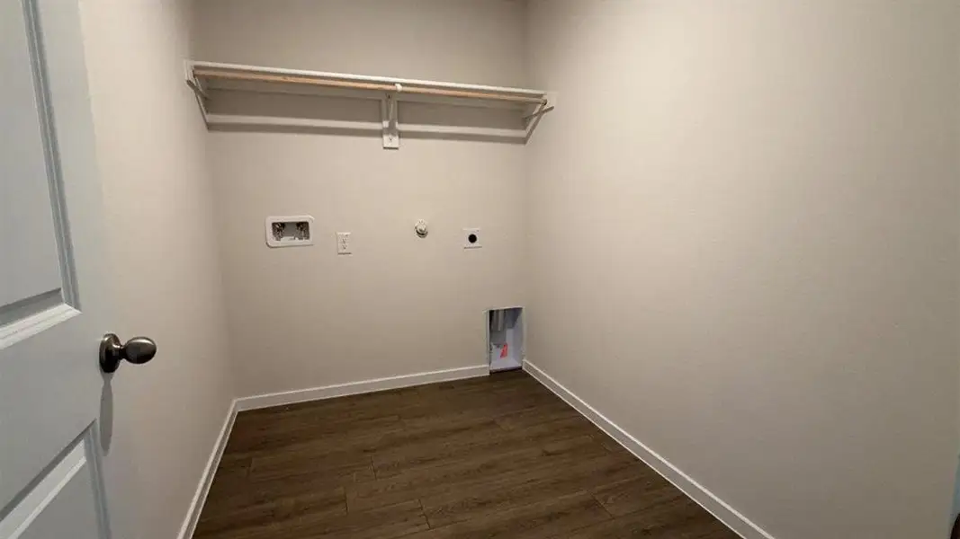 Dedicated utility space featuring neutral wall tones, wood-finish plank flooring, and a single clothing rod Dedicated utility space featuring neutral wall tones, wood-finish plank flooring, and a single clothing rod