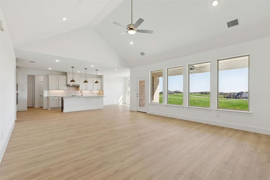Unfurnished living room with light wood-style flooring, recessed lighting, high vaulted ceiling, and ceiling fan