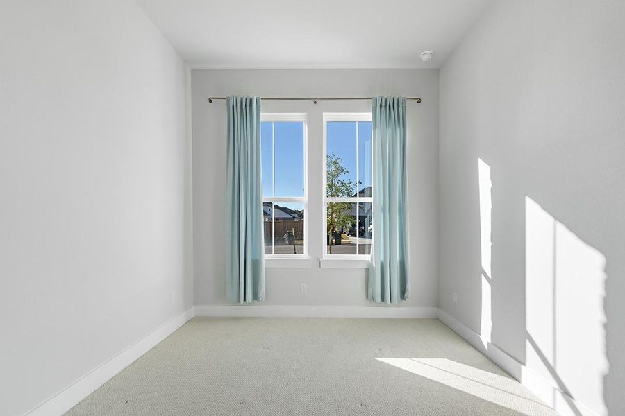 Natural light streams across soft carpeting in this versatile space with tall windows.