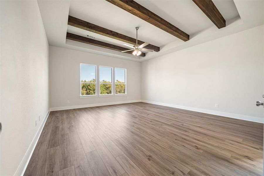 Unfurnished room with wood finished floors, beam ceiling, and a ceiling fan Unfurnished room with wood finished floors, beam ceiling, and a ceiling fan