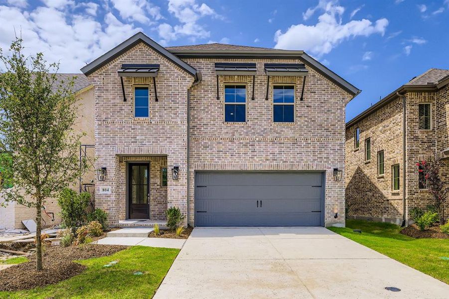 View of front of home with brick siding, driveway, and a garage