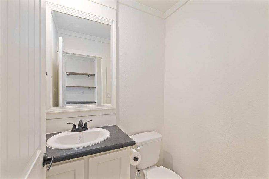 Powder room featuring a white single vanity with a dark countertop, an oval undermount sink, and a black faucet