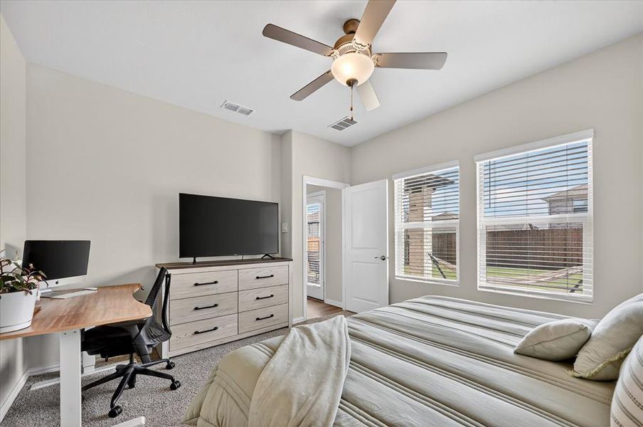 Bedroom with a ceiling fan, an office area, and light carpet