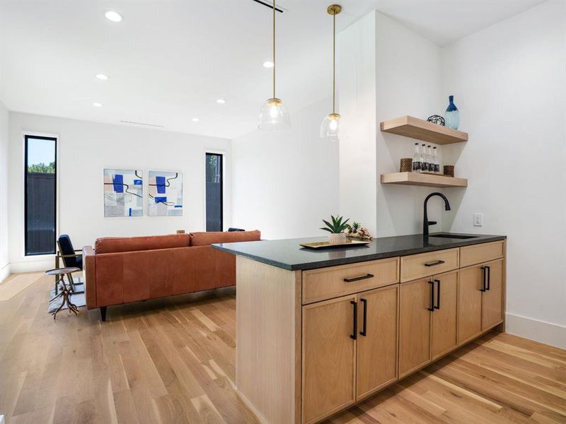 Kitchen with decorative light fixtures, light wood-style floors, open shelves, and open floor plan