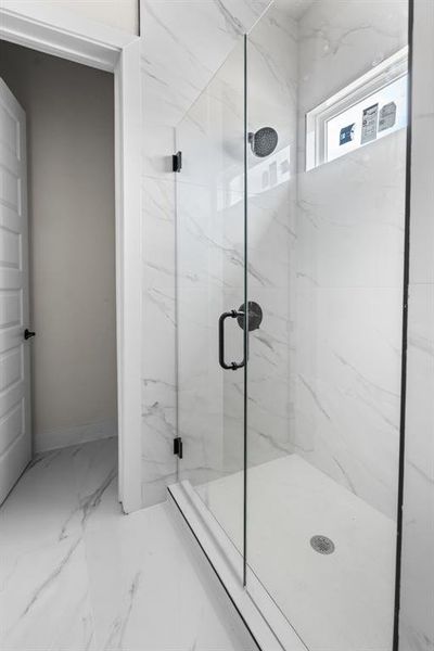 Bathroom with marble look tile flooring and a marble finish shower