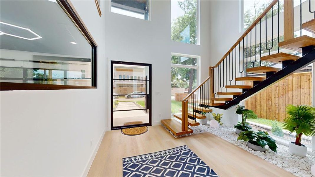 Foyer with stairs, wood finished floors, and a high ceiling