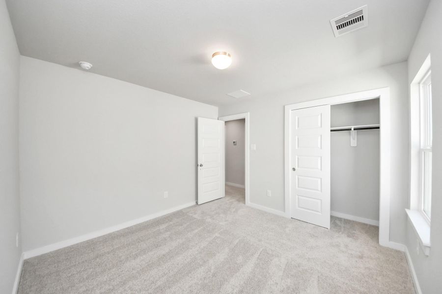 Generously sized secondary bedrooms featuring spacious closets, soft and inviting carpeting underfoot, large windows allowing plenty of natural light, and the added touch of privacy blinds for your personal retreat. Sample photo of completed home with similar floor plan. Actual colors and selections may vary.