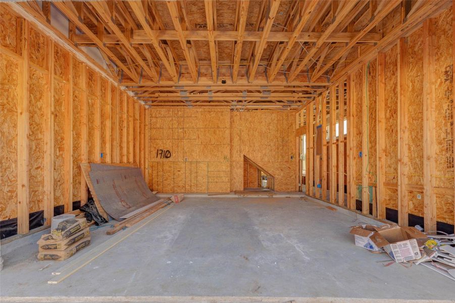 Garage construction view showing a spacious attached garage with exposed framing, concrete flooring, and direct access into the interior of the home. This image highlights the functional entry point, structural progress, and generous garage depth, offering buyers a behind-the-scenes look at the home as it continues toward completion. Garage construction view showing a spacious attached garage with exposed framing, concrete flooring, and direct access into the interior of the home. This image highlights the functional entry point, structural progress, and generous garage depth, offering buyers a behind-the-scenes look at the home as it continues toward completion.