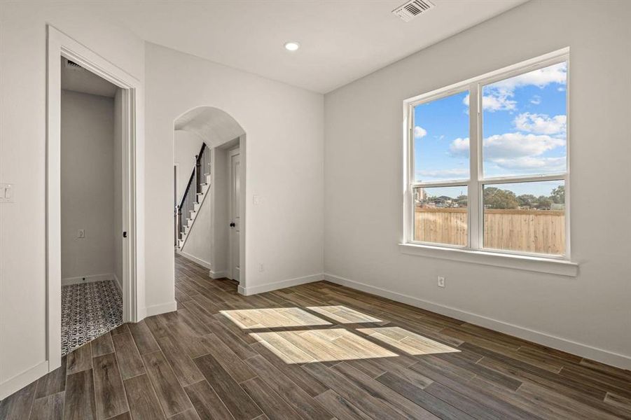 Spare room featuring arched walkways, baseboards, dark wood-type flooring, recessed lighting, and stairs