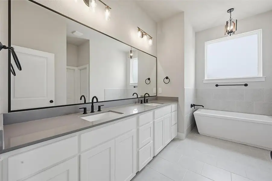 Full bathroom with double vanity, a freestanding bath, and light tile patterned floors