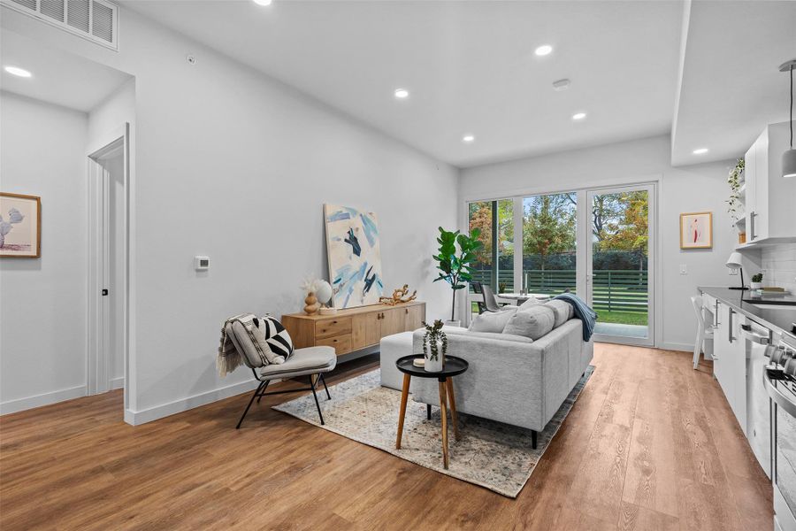 Living area with baseboards, light wood-type flooring, visible vents, and recessed lighting