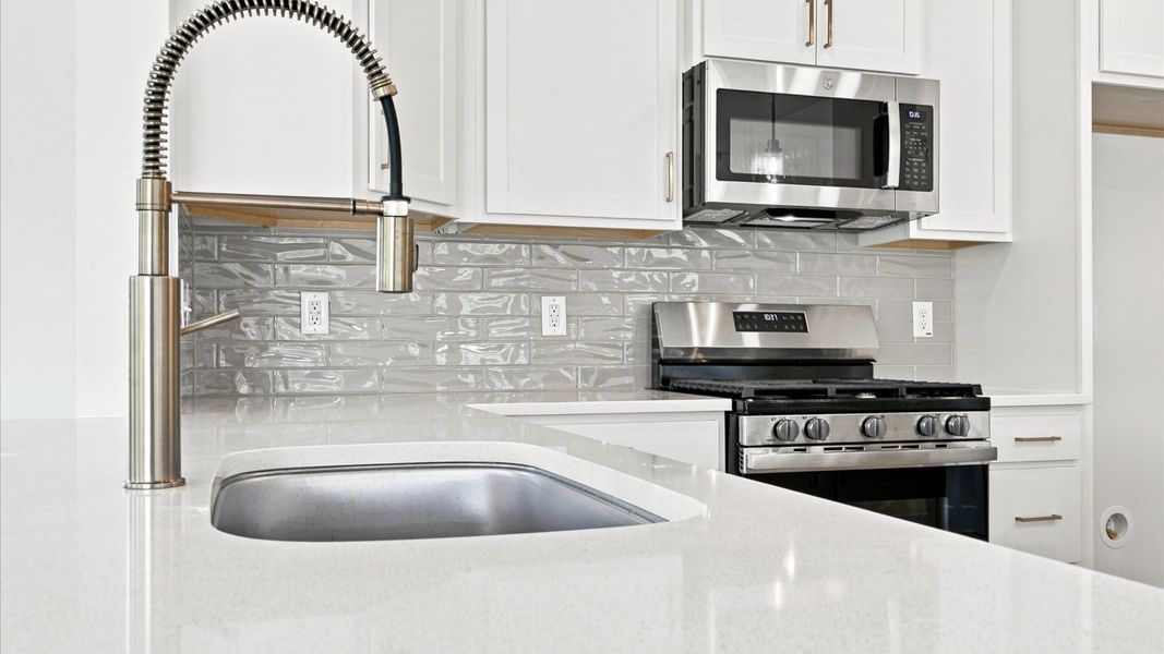 Superior kitchen with quartz countertops, pendant lighting, and a generously sized island