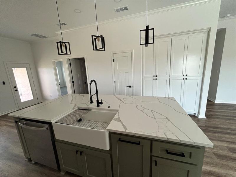 Kitchen with dark wood-type flooring, decorative light fixtures, dishwasher, light stone counters, and gray cabinetry
