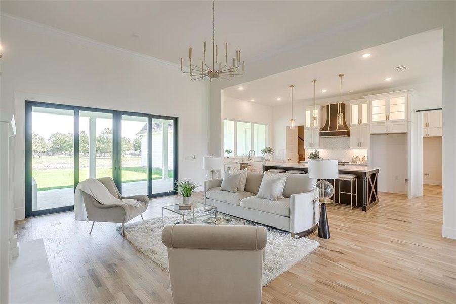 Living room with light wood-type flooring, crown molding, and a chandelier