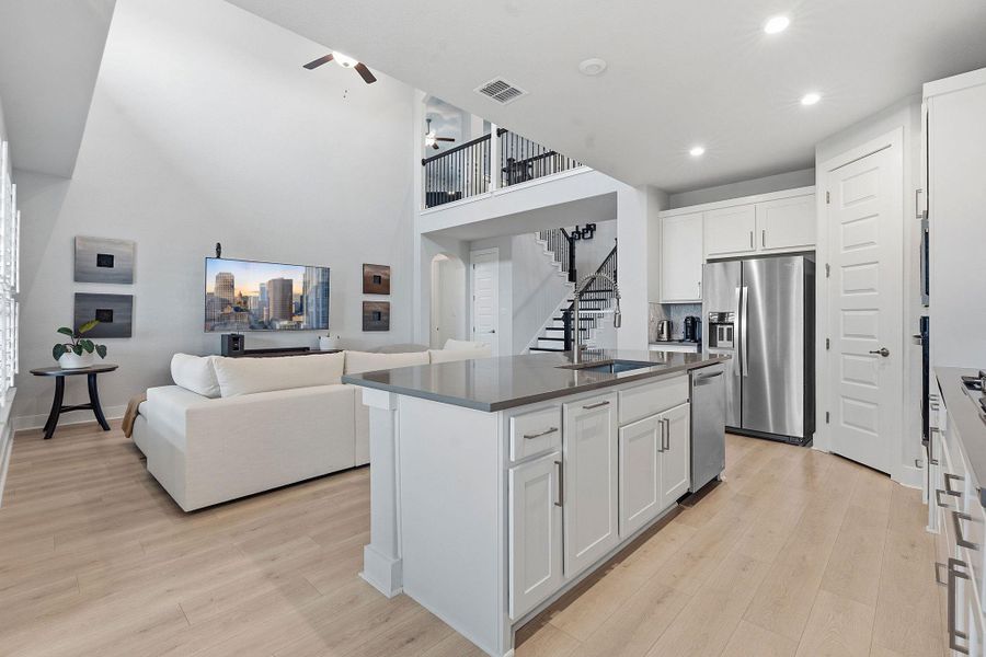 Kitchen with open floor plan, white cabinetry, ceiling fan, a center island with sink, and a high ceiling