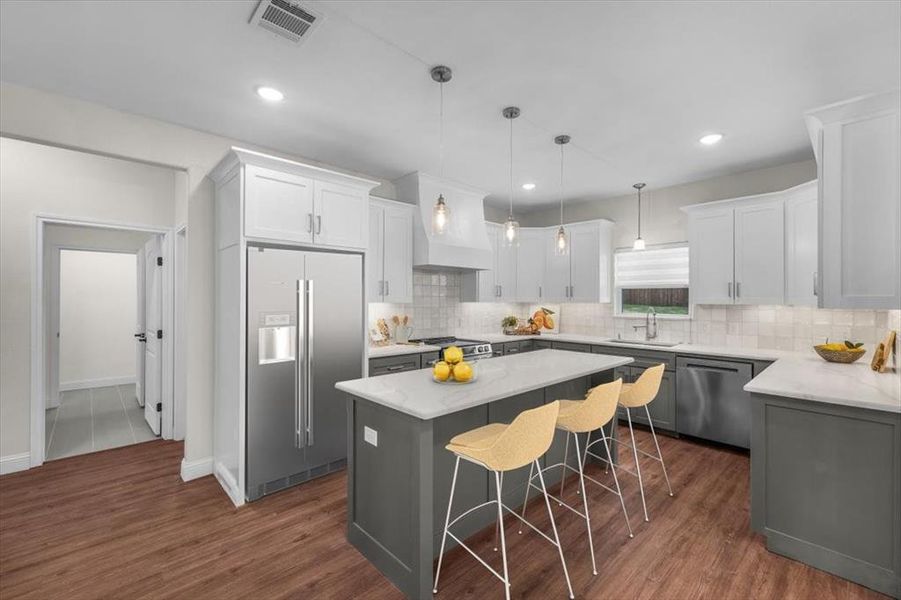 Kitchen with sink, hanging light fixtures, stainless steel appliances, custom range hood, and a kitchen island