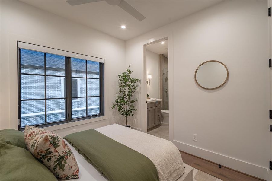 Bedroom with light wood-type flooring, ceiling fan, and ensuite bath