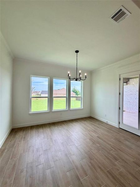 Open concept room featuring wood-finish flooring, three large windows, a glass-paneled exterior door, a black metal chandelier, and crown molding