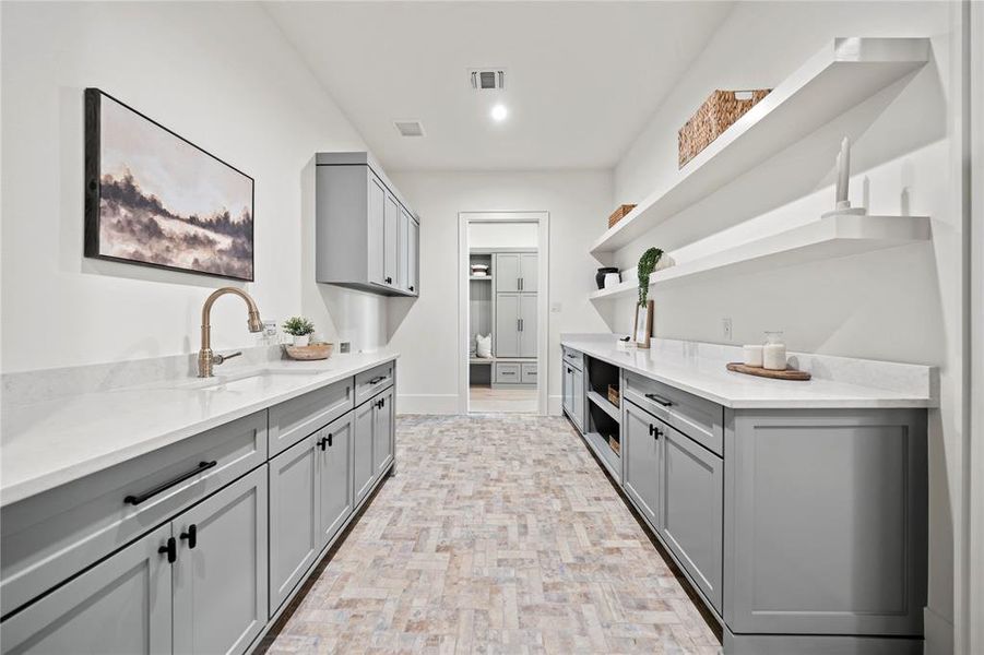 Kitchen featuring gray cabinetry, open shelves, and light stone counters