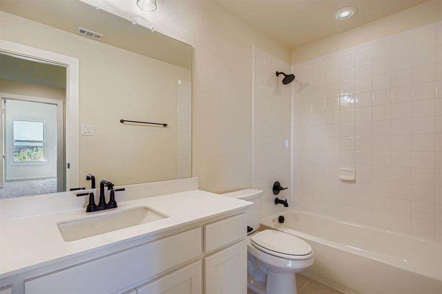 Bathroom featuring shower / tub combination, vanity, and light tile patterned floors