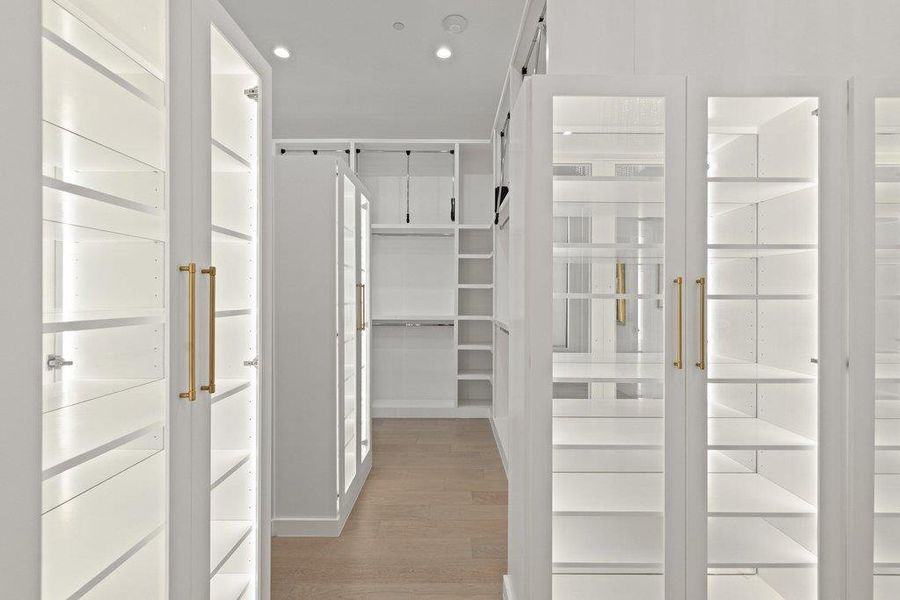 An organized closet system with illuminated shelving and light-colored wood flooring offers ample storage solutions.