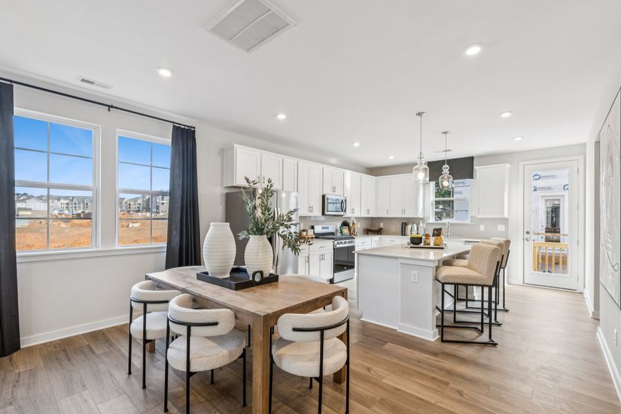 A kitchen with a dining table and chairs.