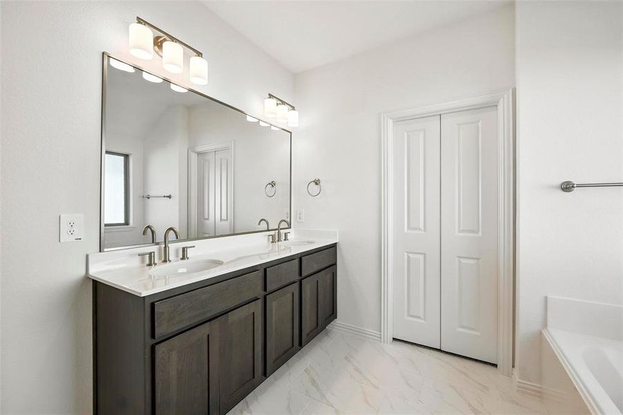 Bathroom with double vanity, a bath, and marble finish flooring