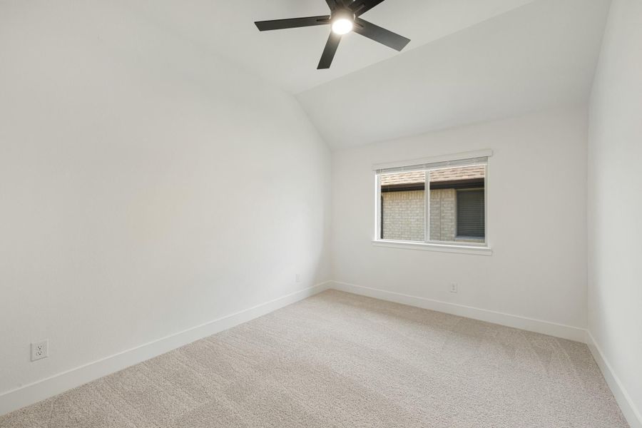 Empty bedroom with vaulted ceiling, black ceiling fan, carpet flooring, and single window