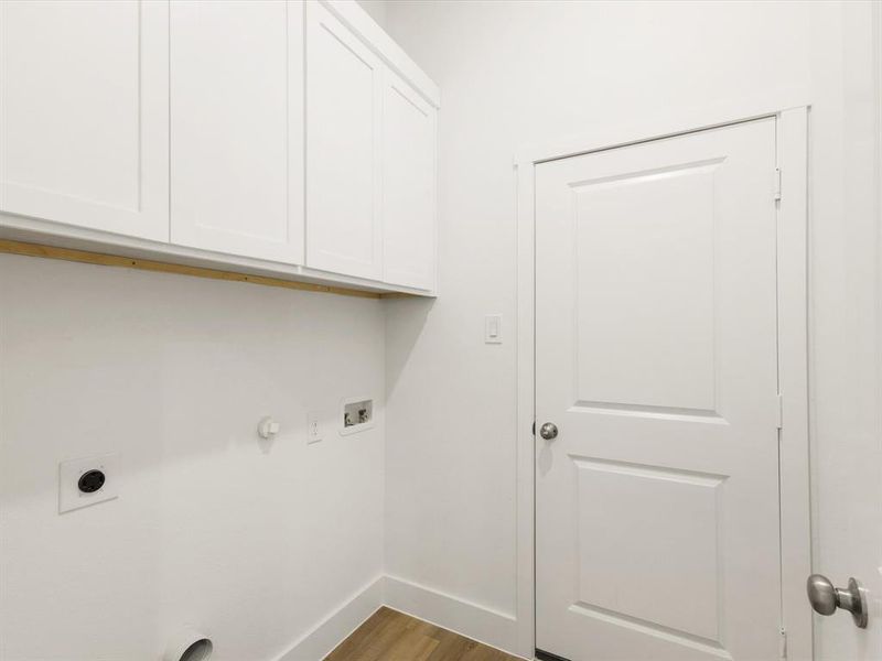 Laundry room with hookup for a gas dryer, cabinet space, wood finished floors, washer hookup, and electric dryer hookup