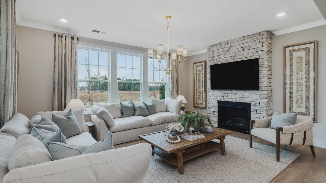 Stonefield home plan open concept family room with stone fireplace and lots of windows Stonefield home plan open concept family room with stone fireplace and lots of windows