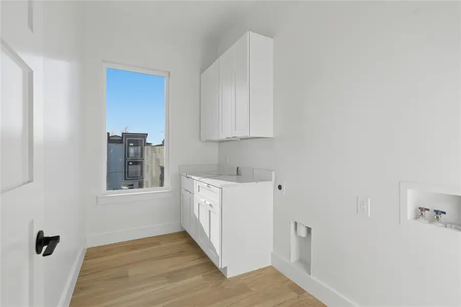 Laundry area featuring light wood-type flooring, cabinet space, hookup for an electric dryer, and hookup for a washing machine Laundry area featuring light wood-type flooring, cabinet space, hookup for an electric dryer, and hookup for a washing machine