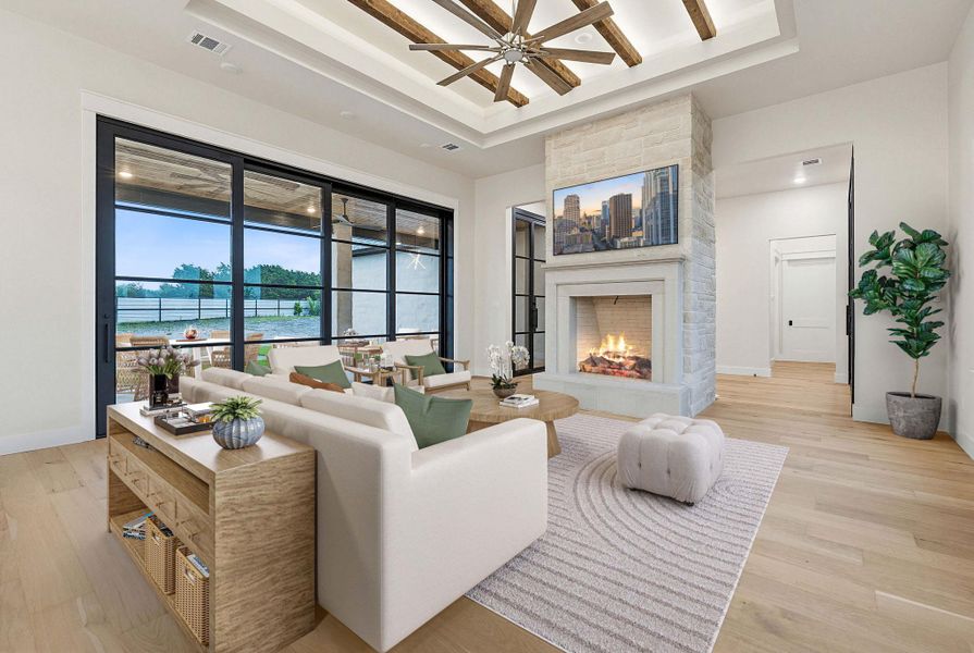 Spacious living area featuring a stone fireplace with a built-in mantel, wood-finish flooring, and a tray ceiling with exposed wood beams