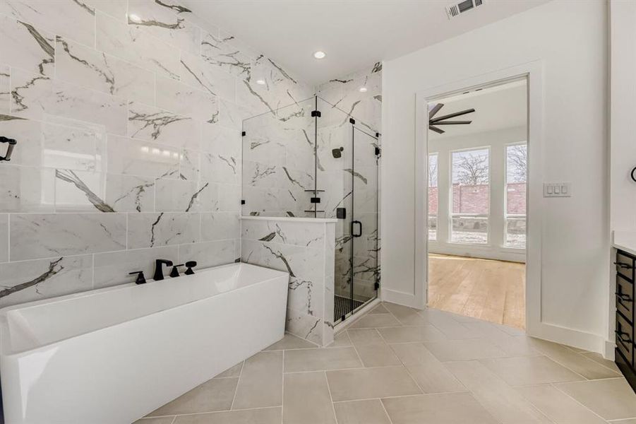 Full bath featuring a freestanding tub, a marble finish shower, light tile patterned floors, vanity, and recessed lighting